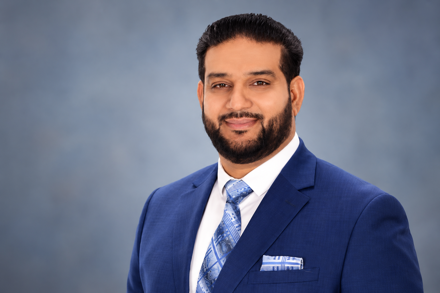 Mandeep Dhaliwal in a navy suit against a neutral background.